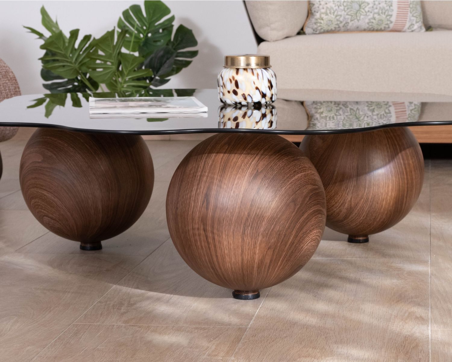 Tavolino dalla forma organica con piano in vetro fumé “Cyléa” e gambe a sfera